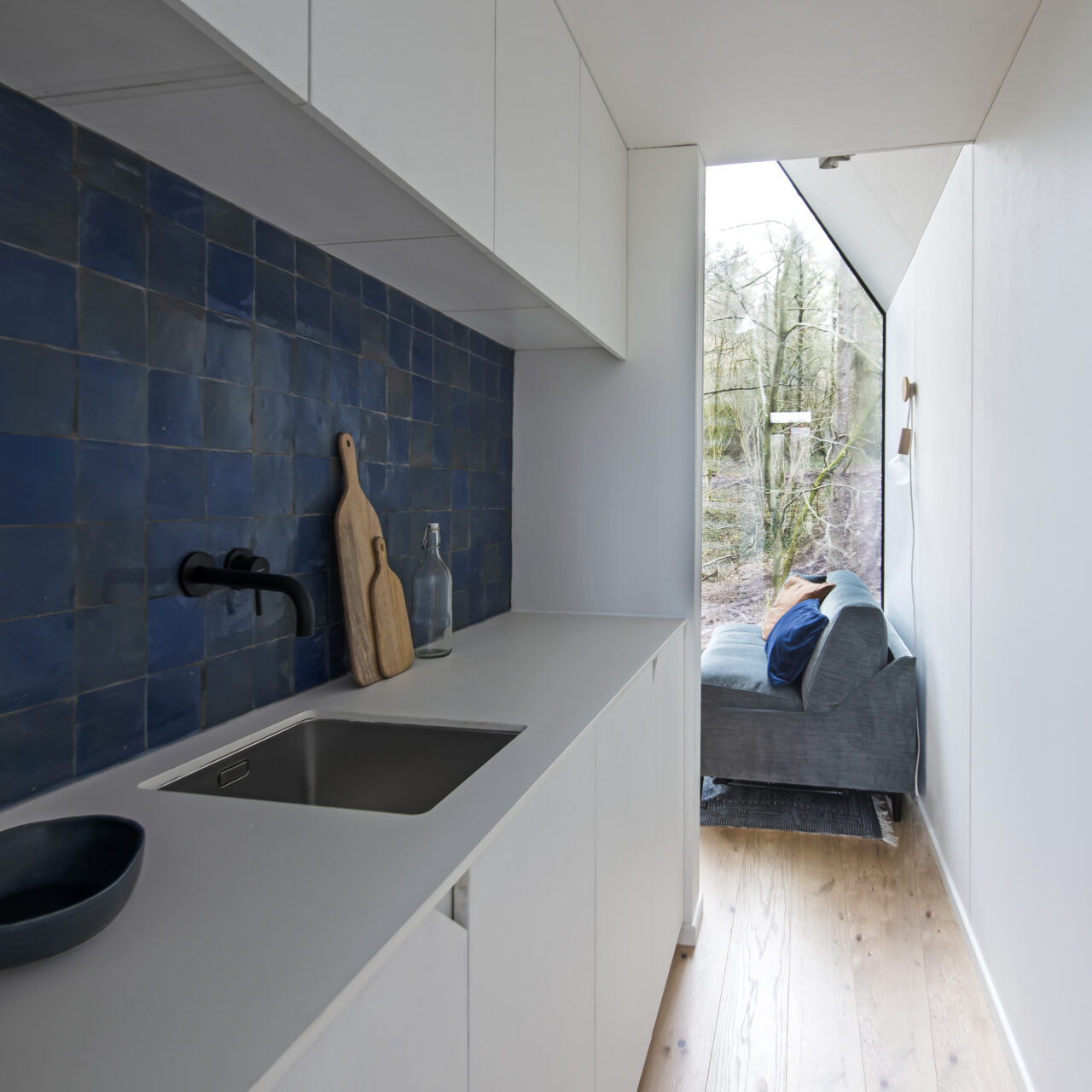 binnenschrijnwerk met witte keuken met blauwe fiances en zetel